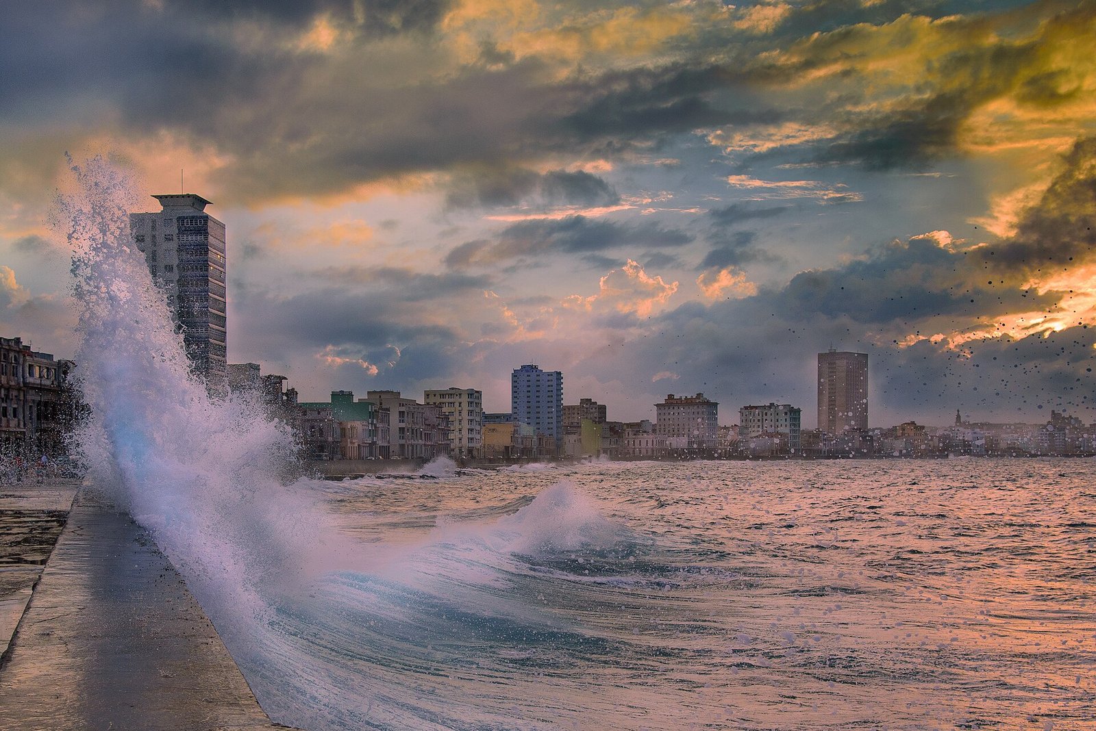 Una ola rompe contra el muro del Malecón de La Habana al atardecer