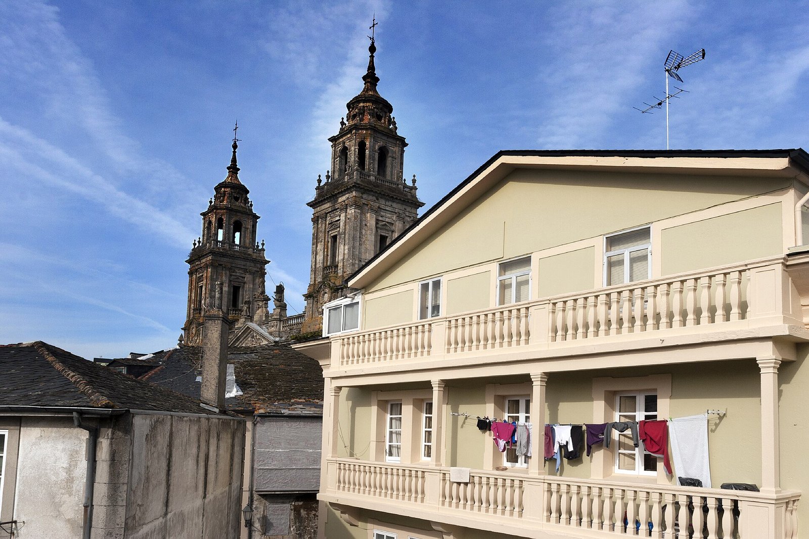 Torres de la catedral de Lugo asomando sobre los tejados de pizarra, con ropa tendida en un balcón
