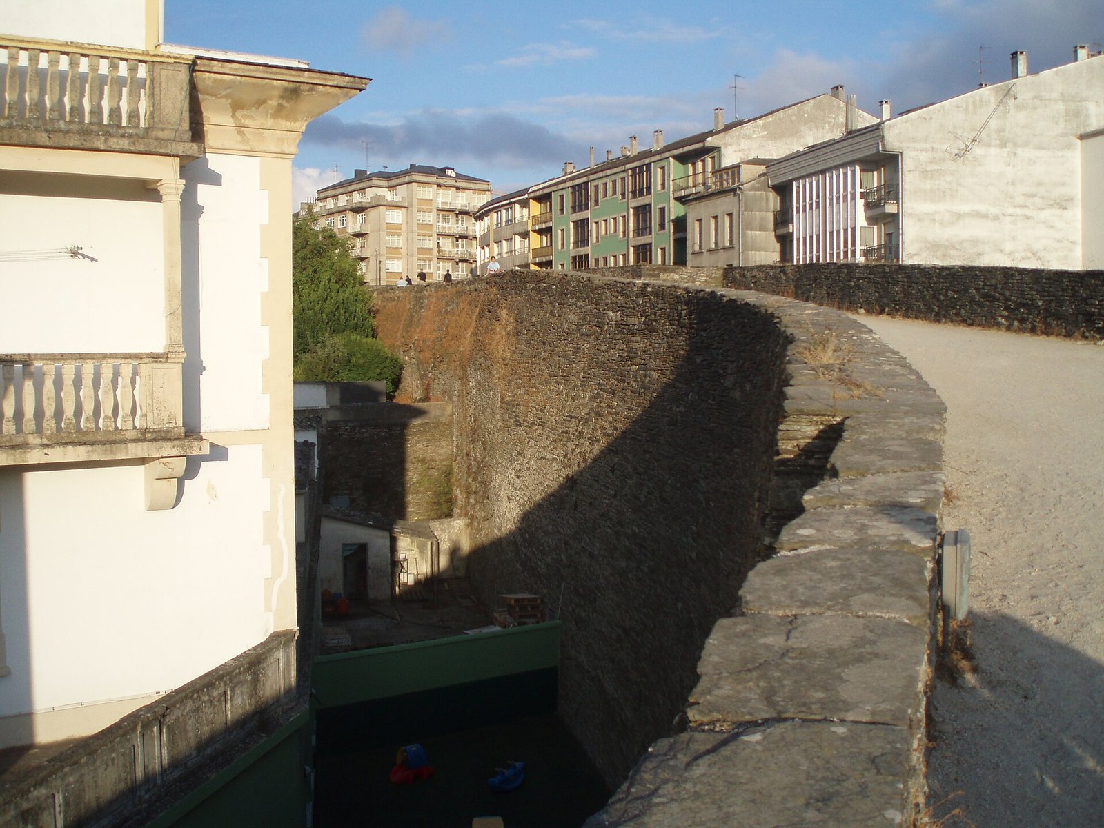 Adarve de la Muralla de Lugo, de piedra de pizarra, curvándose entre edificios
